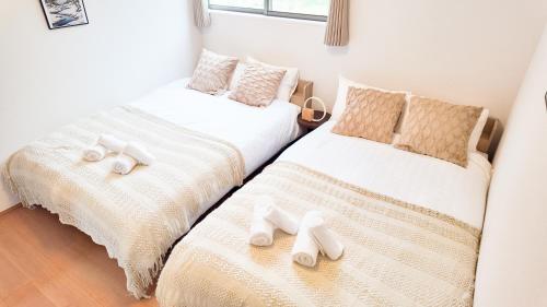 two beds in a room with white sheets and slippers at 9stay 富士河口湖 in Fujikawaguchiko
