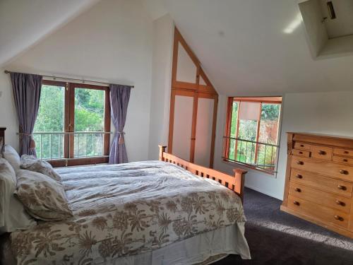 a bedroom with a bed and a dresser and windows at Paradise in the city in Christchurch
