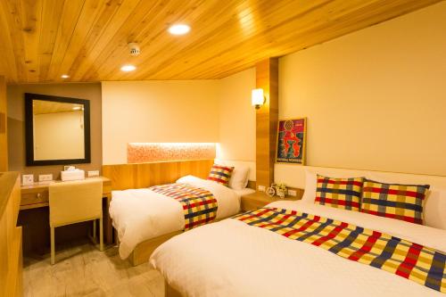 a bedroom with two beds and a desk and a mirror at W Hostel in Tainan