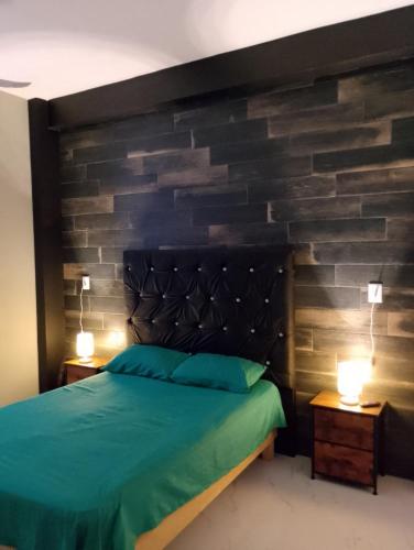a bedroom with a green bed and a brick wall at Casa en Paraíso Cuautla Morelos in Cuautla Morelos