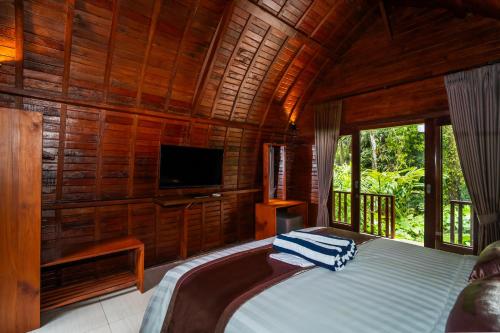a bedroom with a bed and a tv in a room at Udaka Retreat in Payangan