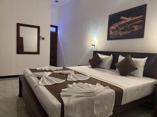 a bedroom with a large bed with white sheets at Dilaro Rest & Villa in Kottagoda