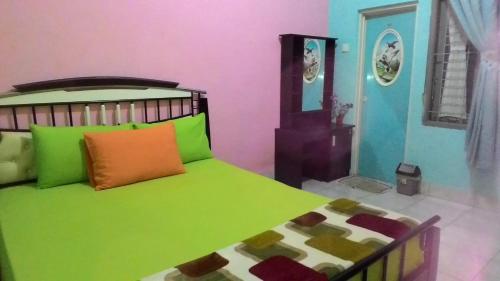 a bedroom with a bed with green and orange pillows at Ruqita Homestay in Airtabit