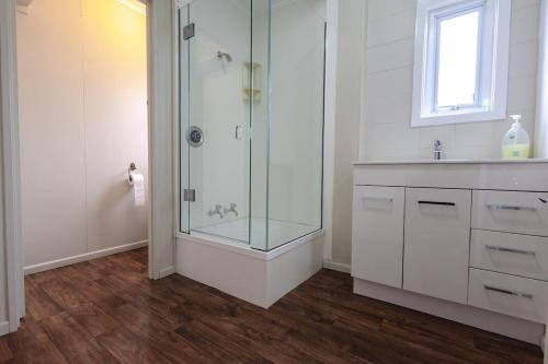 a bathroom with a glass shower and a sink at Clock Tower Accommodation in Hokitika