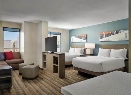 a hotel room with two beds and a couch at Hyatt House LA - University Medical Center in Los Angeles