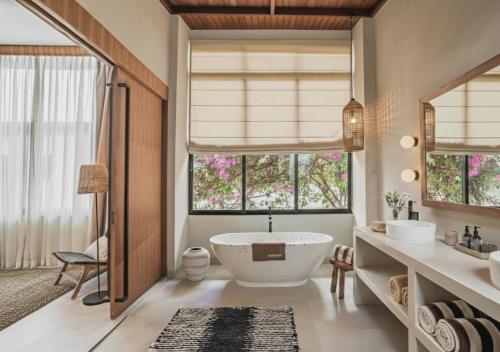 a bathroom with a tub and a large window at La Brava Bali I Private Luxury Villas in Bingin, Uluwatu in Uluwatu