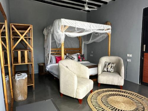 a living room with a canopy bed and two chairs at Happy Villas in Paje