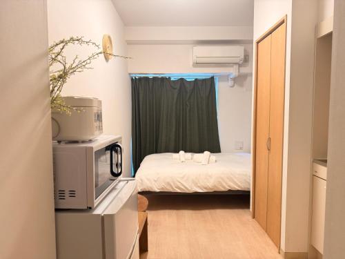 a small room with a bed and a microwave at Uhome Kanda Hotel in Tokyo