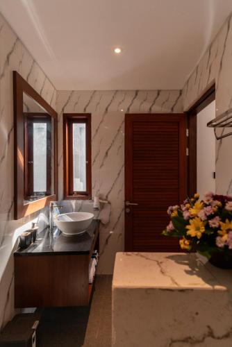 a bathroom with a sink and a mirror and flowers at Villa Mesari Bona in Blahbatu