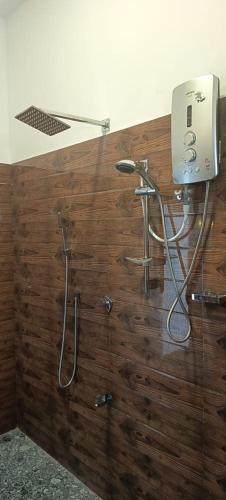a shower in a bathroom with a wooden wall at Loveena by H.S. Restaurant & Guest in Tangalle