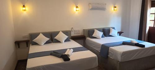 two beds in a hotel room with two bedsitures at Loveena by H.S. Restaurant & Guest in Tangalle