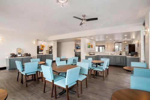 a dining room with blue chairs and tables and a kitchen at Quality Inn Foley - Gulf Shores North in Foley