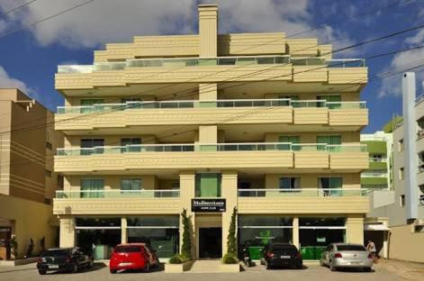 un grande edificio con macchine parcheggiate di fronte di Mediterraneo Home Club a Bombinhas