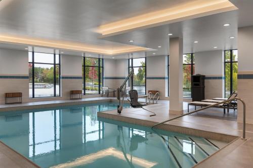 a swimming pool with a table and chairs in a building at Hyatt Place Toronto Airport in Toronto