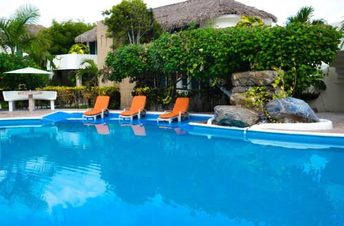 a swimming pool with orange chairs and a house at Bon Jesus Hotel in Costa Esmeralda