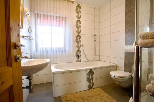 a bathroom with a sink and a toilet and a tub at Almhaus Karantanien in Hochrindl