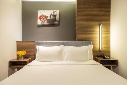 a bedroom with a bed with white sheets and flowers at LiT BANGKOK Residence in Bangkok