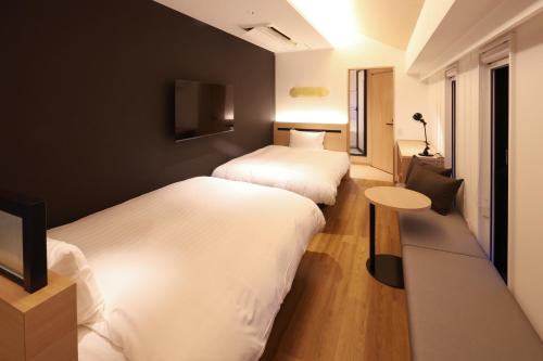 two beds in a small room with a table and a table at HATAGO HIKONE - Main building in Hikone
