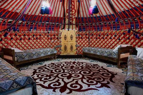 a interior of a yurt with two beds and a rug at Komay Yurt Camp Karakol in Karakol