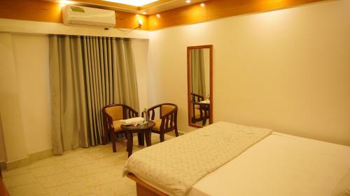 a bedroom with a bed and a table and chairs at Hotel Dhanmondi Prime in Dhaka