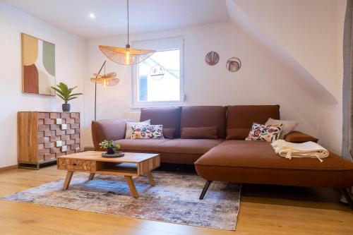 a living room with a brown couch and a table at Heimbi Home No 2 I 4-5 Personen I Familienfreundlich I Balkon I Nähe EuropaPark I Parkplatz I E Ladestation in Schwanau