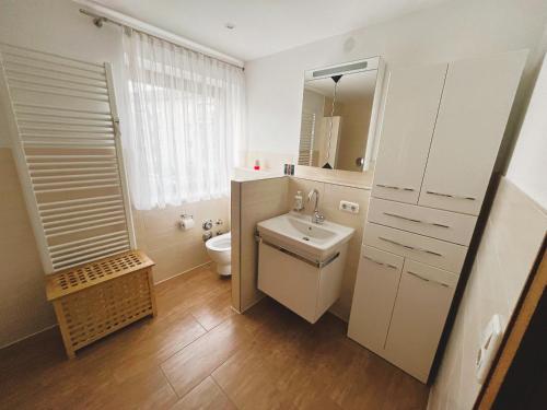 a white bathroom with a sink and a toilet at Gemütliche Maisonette nahe der längsten Burg der Welt in Burghausen