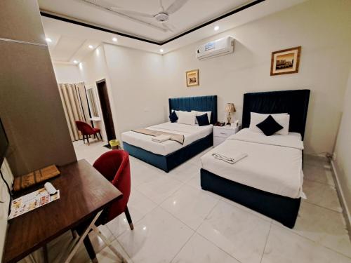 a hotel room with two beds and a desk at Cuzzy Inn Stay in Lahore