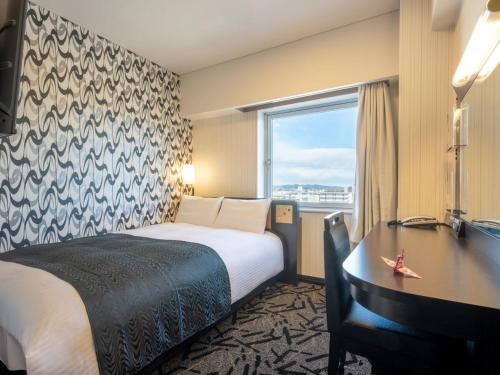 a hotel room with a bed and a desk and a window at APA Hotel Gunma Otaeki-Kita in Ota