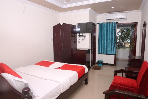 a bedroom with a bed and a red chair at Sai Kirshanth Residency in Karaikal