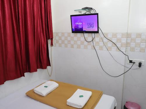 a room with a bed with a tv on the wall at Shree Residency in Airoli