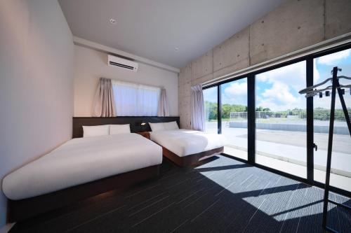 a bedroom with two beds and a large window at クリスタルヴィラ大浦 in Miyako-jima