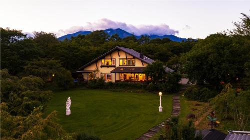 a house on a lawn with mountains in the background at ReTune Hokuto in Hokuto