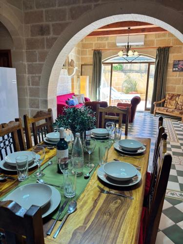 a wooden table with plates and glasses on it at Ta Carmen Farmhouse with pool in Qala