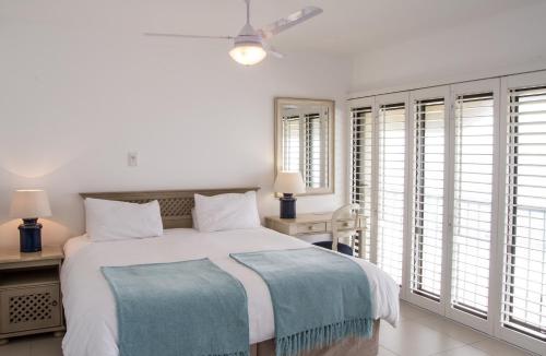 a white bedroom with a bed and windows at 802 The Bermudas - by Stay in Umhlanga in Durban