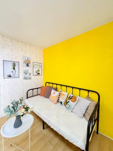 a yellow room with a bed with pillows and a table at Your Comfort Zone Staycation1 in Manila