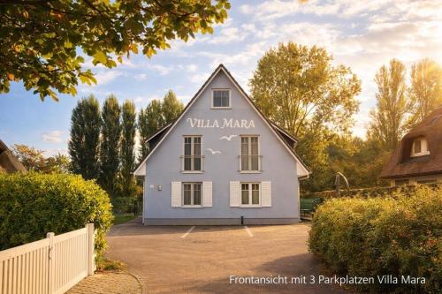 a white house with a sign on the side of it at Villa Mara - für 12 Gäste, Sauna, 1 Wirlwanne, 2 Duschen, Kamin, 5 SZ, 3 WC, Highspeed Internet, abgezeuntes Grundstück in Glowe