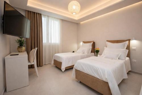 a hotel room with two beds and a flat screen tv at Hotiday Torre Pali Spiaggia in Torre Pali