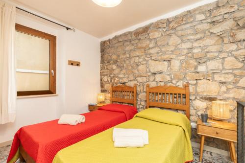 two beds in a room with a stone wall at Climbing House in Baunei