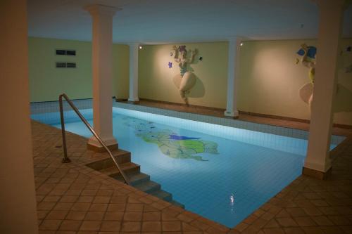 a large swimming pool with a tile floor at Restaurant Hotel Merlet in Schoorl