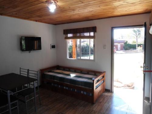 a room with a bed and a table and a window at Cabañas 57 in Villa Carlos Paz