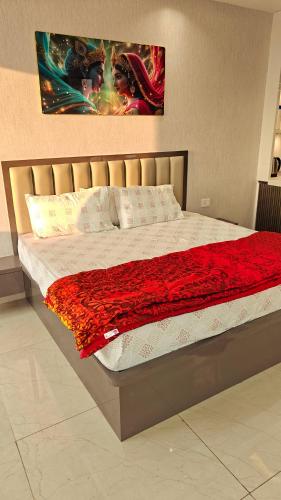 a bed with a red blanket and a painting on the wall at Anandam in Vrindāvan