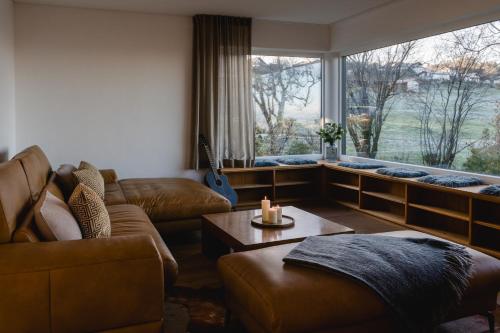 a living room with a couch and a large window at PanoramaLodge Samerberg in Samerberg