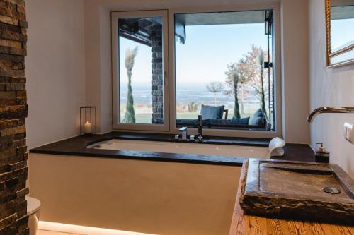 a bathroom with a tub and a large window at PanoramaLodge Samerberg in Samerberg
