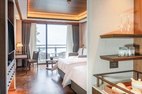 a hotel room with a bed and a desk and a window at Dusit Thani Himalayan Resort Dhulikhel, Nepal in Dhulikhel
