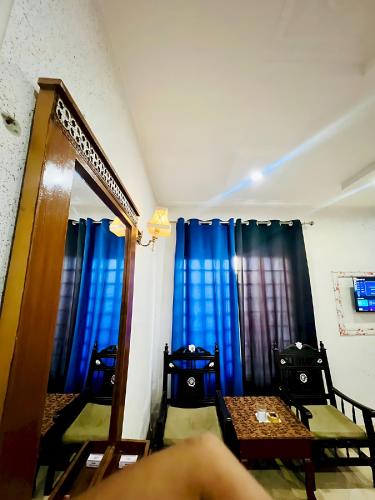 a room with blue curtains and a table and chairs at Hotel Marvi Multan in Multan