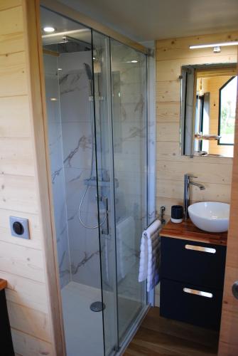 a bathroom with a glass shower and a sink at Tiny House - La P'tite Georgette in Canouville