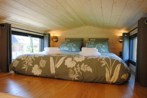 a large bed in a room with a wooden floor at Tiny House - La P'tite Georgette in Canouville