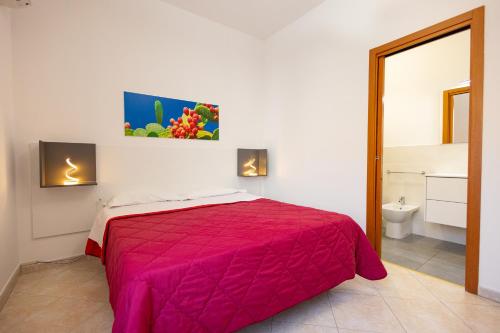 a bedroom with a red bed and a bathroom at CasaTrapani in Trapani