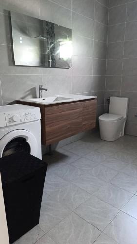 a bathroom with a sink and a washing machine at Résidence LE MÄYSA in Sada