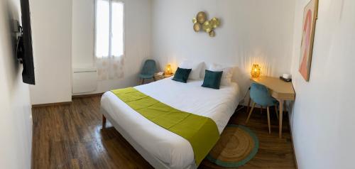 a hotel room with a bed and a desk and a bed at Hotel De Provence in Digne-les-Bains